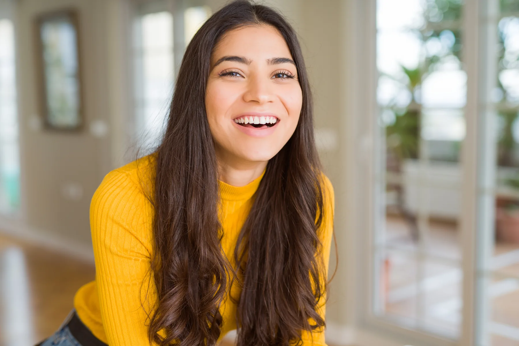Smiling Young Woman in Yellow Sweater Smiling young woman in a yellow sweater indoors